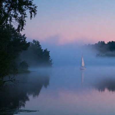 Sailboat on foggy lake at dawn