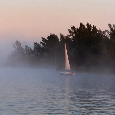 Sailboat on misty water at dawn