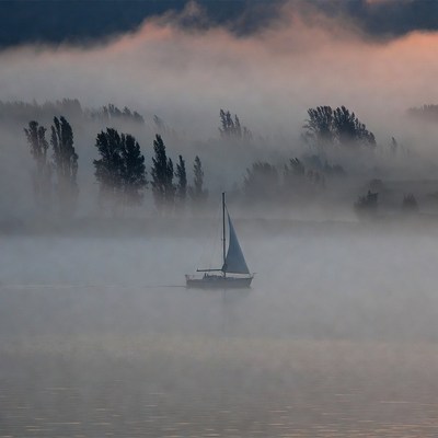 Sailboat on foggy water at dawn