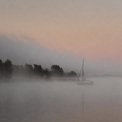 Sailboat on a foggy river at dawn