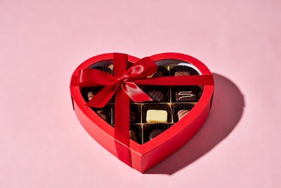 Heart-shaped box of chocolates on pink surface