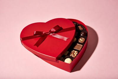 A red heart-shaped box holds assorted chocolates