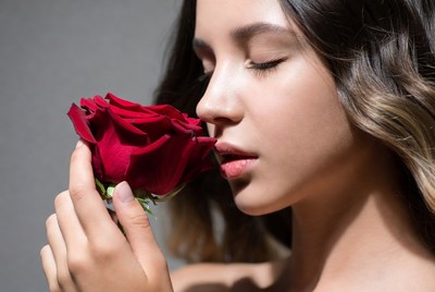 Woman smelling red rose outdoors