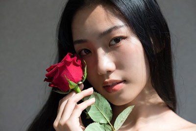 Young woman holding a rose gently