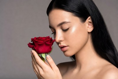 Woman holding rose close to face