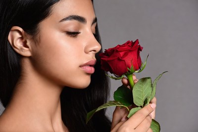 Woman holding red rose close to face