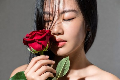 Woman holding a rose close to her face