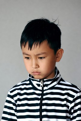 Boy with striped jacket looking down