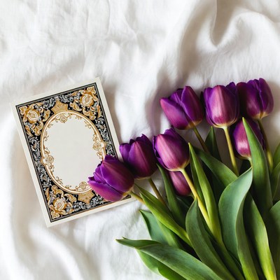 Purple tulips and card on white fabric