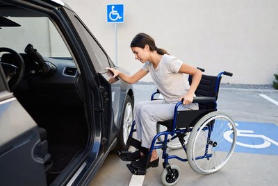 Woman using wheelchair to enter car
