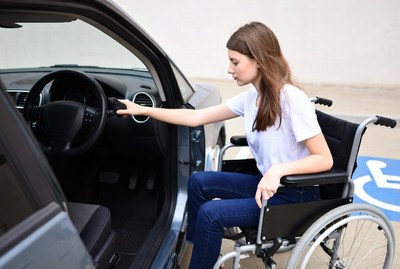 Young woman in wheelchair enters car