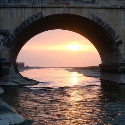 Sunset under a stone bridge
