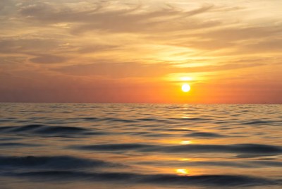 Sunset over smooth ocean water