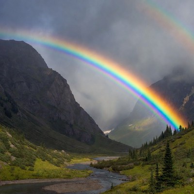 Rainbow over mountain valley at sunset