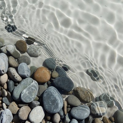 Clear water over smooth stones by the shore