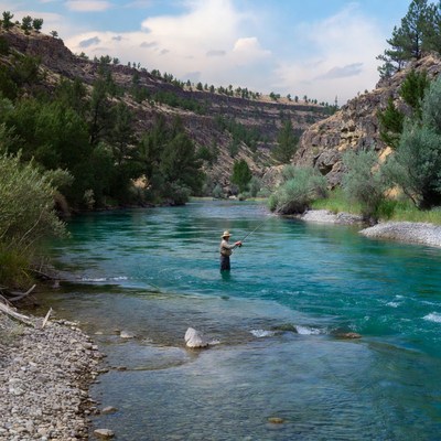 Man fishing in a river near hills
