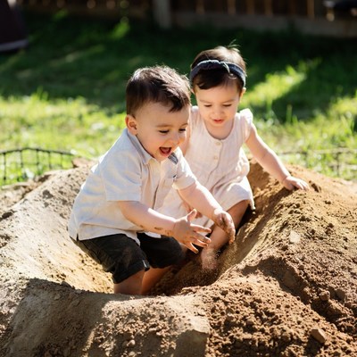 Children play in sandbox during sunny day