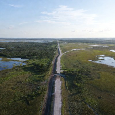 Road through grassy wetlands near water