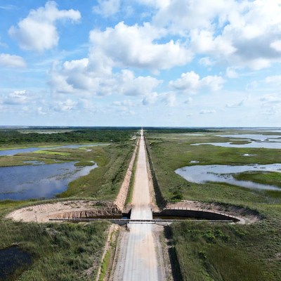 Road through wetlands in clear sky