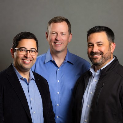 Three men standing together in office setting