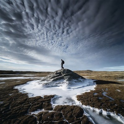 Hiker on rocky terrain under clouds