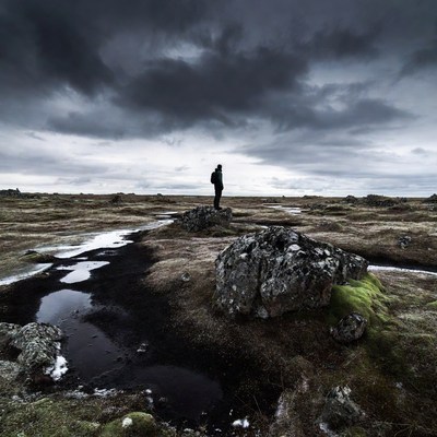 Standing on rocky ground under dark clouds