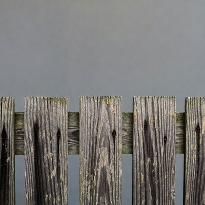 Weathered wood fence against gray wall