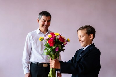 Boy gives flowers to man