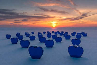 Large blue hearts on snowy field at sunset
