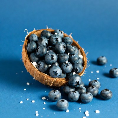 Blueberries in coconut bowl on blue surface