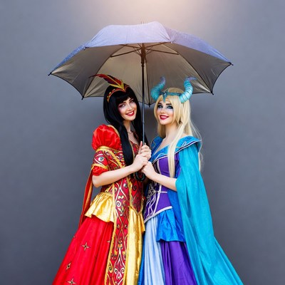 Two women in costumes under umbrella