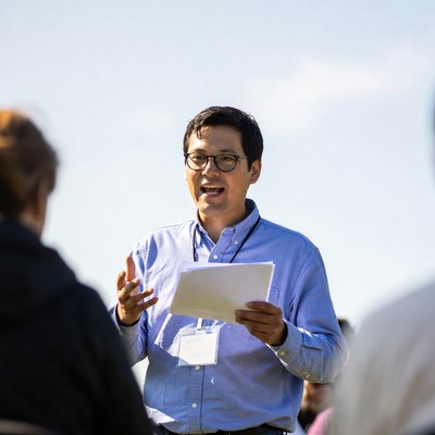 Man speaking to group outdoors in bright weather