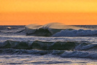 Waves crash at sunset over the ocean
