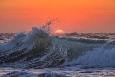 Waves crash at sunset over ocean