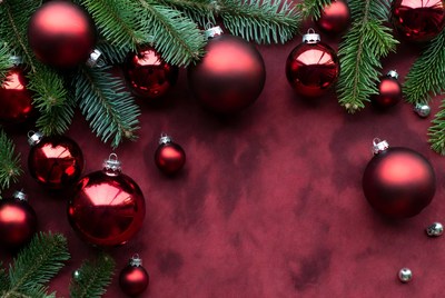 Red ornaments and green branches on table