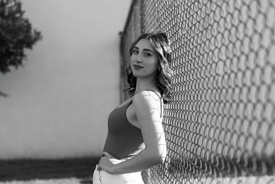 Woman poses by a chain-link fence