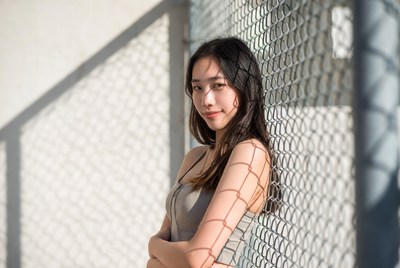 Young woman stands by fence