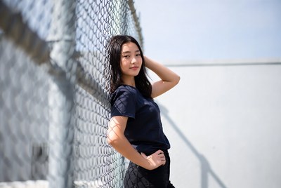 Young woman poses by fence