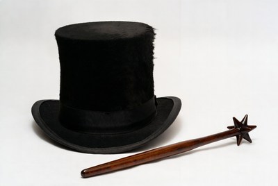 Black hat and magic wand on white background
