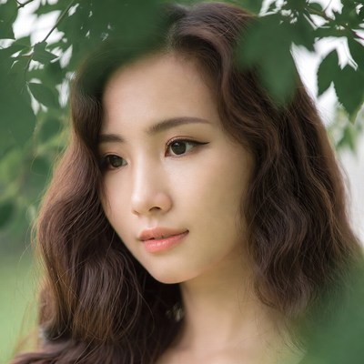 Young woman among green leaves