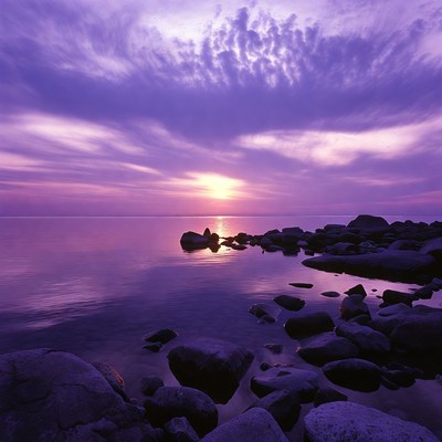 Sunset over calm water with stones