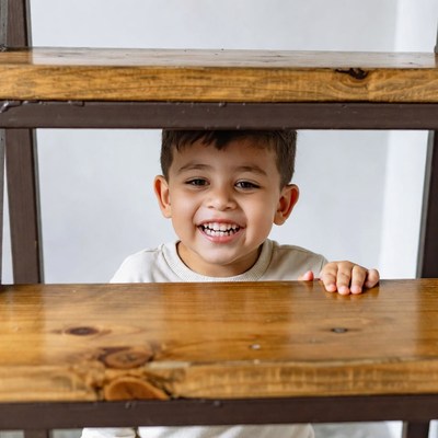Boy smiling behind wooden shelf
