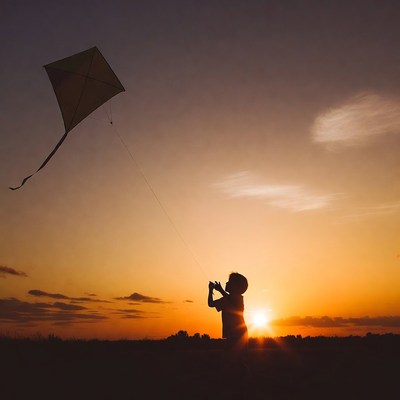 Child flying a kite at sunset