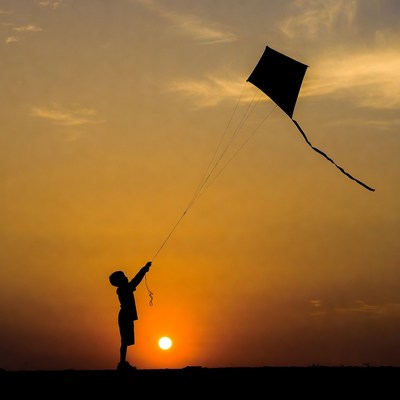 Boy flying kite at sunset