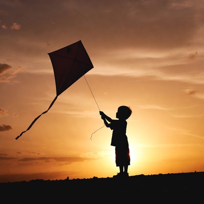 Child flying a kite at sunset