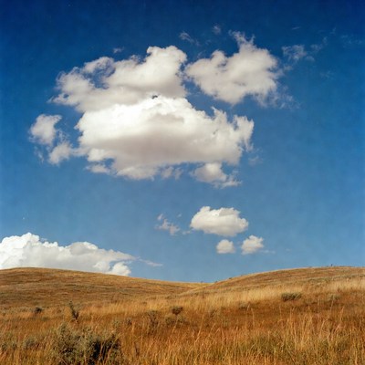 Clouds over grassy hills in bright sky