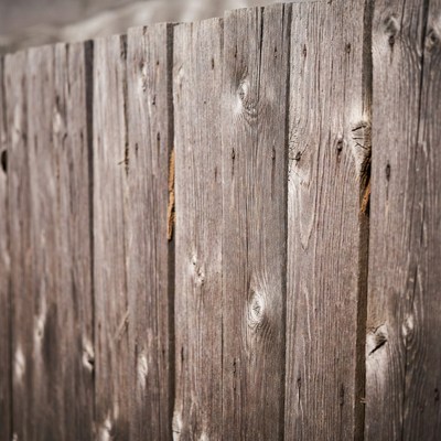 Wood fence with weathered planks in sunlight