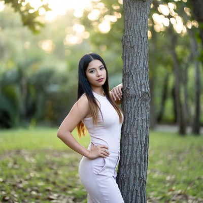 Woman posing by tree in park