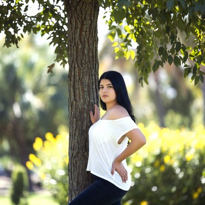 Young woman poses by a tree