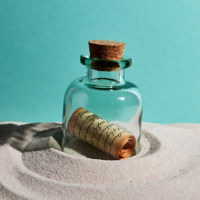 Message inside a glass bottle on sand